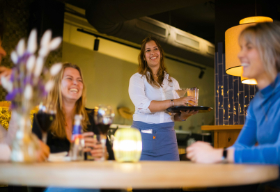 Bediening en gasten met een lach op hun gezicht tijdens het diner
